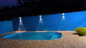 a blue swimming pool in a yard at night at Cantinho,RMA in Bom Jesus dos Perdões