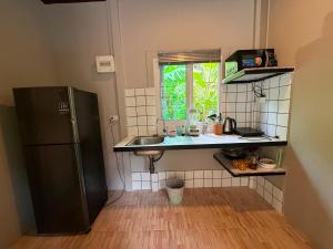 a small kitchen with a sink and a refrigerator at Serenity House with Large terrace in Ban Nok