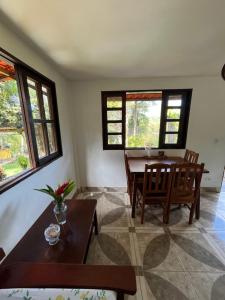 a living room with a table and chairs and windows at Casa de Marina in Palmeiras