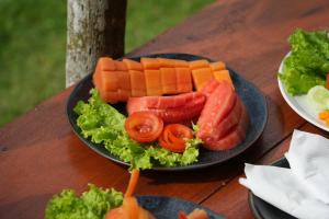 a plate of carrots and lettuce and tomatoes on a table at De Sila House and Pool in Tembuku