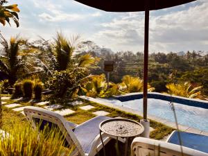 a patio with a table and chairs next to a pool at De Sila House and Pool in Tembuku