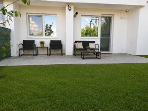 a patio with chairs and a grass yard at Steffi Apartment in Balş