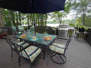 a table with chairs and an umbrella on a deck at LAKEFRONT CHALET in THE BURCHES in Tobyhanna