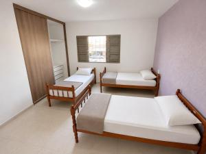 a room with three beds and a mirror at Morada 360 Casa Inteira para até 09 Pessoas in Sumaré