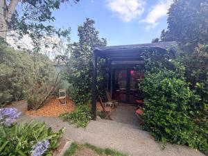 a black shed with a table and chairs in a garden at Mustang Studios in Canberra