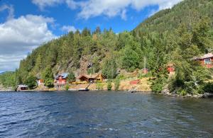 a river with houses on the side of a mountain at Lakefront Cabin on Vråvatn in Kviteseid