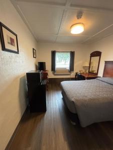 a room with a bed and a desk and a window at Martin House Motel in Brookfield