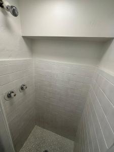 a bathroom with a shower with white tile at Martin House Motel in Brookfield