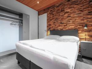 a bedroom with a white bed and a brick wall at Seeglück am Pressegger See in Lake Pressegg