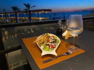 a table with a plate of food and a glass of wine at Hotel Brigeni & Camping Riviera in Shëngjin