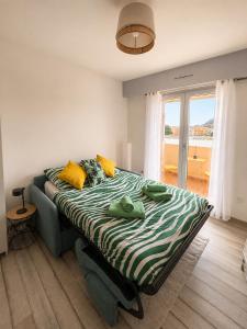 a bedroom with a bed with yellow pillows and a window at Lovely studio with balcony - central location in Cavalaire-sur-Mer