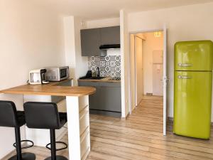 a kitchen with a table and a green refrigerator at Lovely studio with balcony - central location in Cavalaire-sur-Mer
