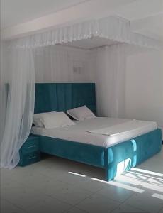 a bed in a white room with a blue bed frame at Wrens cosy home in Diani Beach