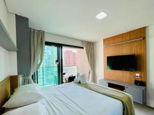 a bedroom with a large bed and a tv at Beach Class Meireles by HostFacil in Fortaleza