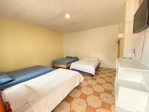 a room with two beds and a flat screen tv at Hostería del Puerto in Puerto López