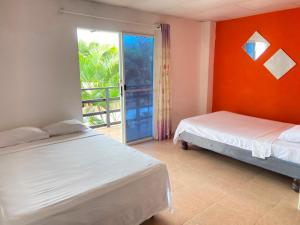 two beds in a room with an open door at Hostería del Puerto in Puerto López