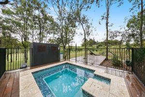 a swimming pool on a deck with a fence at Fig Tree Luxury Guest House in Pokolbin