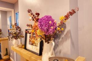 a white vase filled with flowers on a table at Fig Tree Luxury Guest House in Pokolbin