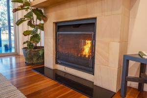 a fireplace in a living room with a fire in it at Fig Tree Luxury Guest House in Pokolbin