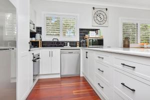 a kitchen with white cabinets and a clock on the wall at Lamp Estate in Greta