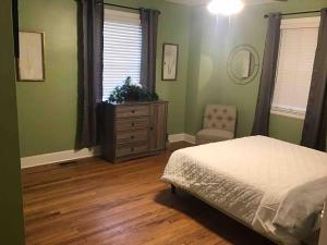 a bedroom with green walls and a bed and a dresser at Cute 2 bedroom house in Augusta in Augusta