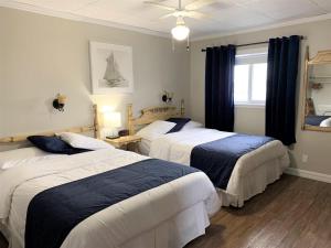 a bedroom with three beds and a window at Complexe Cap-Chat in Cap-Chat