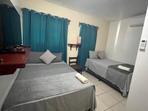 two beds in a room with blue curtains at Hotel Comfort Trujillo in La Milagrosa