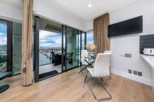 a living room with a table and chairs and glass windows at Sun Soaked Corner Apartment with Harbour View in Auckland
