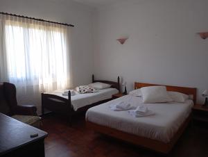 a bedroom with two beds and a chair and a window at Casa D'Afife in Afife