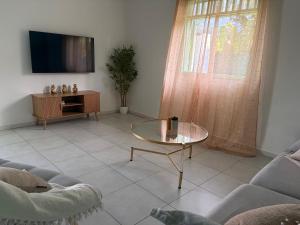 a living room with a glass table and a tv at Villa de charme à Matoury in Matoury