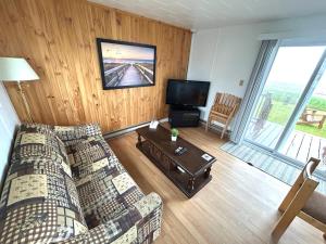 a living room with a couch and a tv at Complexe Cap-Chat in Cap-Chat