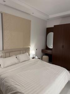 a bedroom with a large white bed and a mirror at City residence in Medina