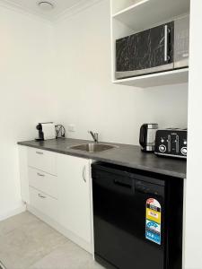 a kitchen with a sink and a black dishwasher at Home Inn Timaru in Timaru