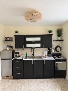 a kitchen with black cabinets and a sink and a stove at Casa Brisa Beach House in Dorado