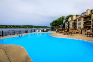 a large blue swimming pool with tables and chairs at Pool Days & Water Fun Await: Lake Ozark Escape! in Lake Ozark