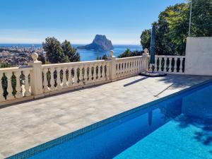 a swimming pool with a fence and a view of the ocean at Bona Vista in Calpe