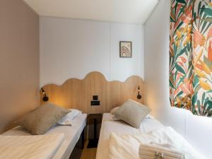 two beds in a room with white walls at New Vennepark caravan 463 6p in De Haan