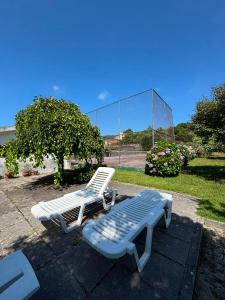 two white chairs and a bench and a glass building at Casa D'Afife in Afife