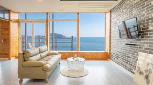 a living room with a couch and a view of the ocean at Geoje Inbito Pension in Op'o