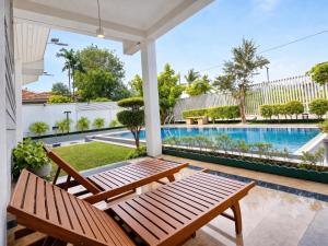 a patio with two wooden benches and a swimming pool at Apna Colombo in Nawala