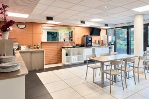 a kitchen and dining room with a table and chairs at Comfort Aparthotel Versailles, St Cyr l'Ecole in Saint-Cyr-lʼÉcole