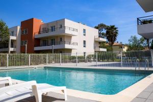 a swimming pool in front of a building at Comfort Aparthotel Cannes Mandelieu in Mandelieu-La Napoule