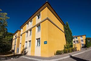 a yellow and white building on the side of a street at Comfort Aparthotel Aix Le Tholonet in Aix-en-Provence
