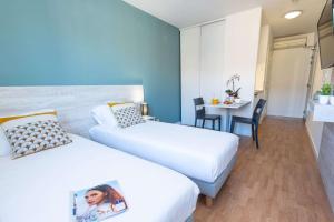a hotel room with two beds and a table at Comfort Aparthotel Aix Le Tholonet in Aix-en-Provence