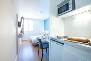 a small kitchen with a table and a bed at Comfort Aparthotel Aix Le Tholonet in Aix-en-Provence