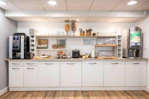 a kitchen with white cabinets and a refrigerator at Comfort Aparthotel Besancon La City in Besançon