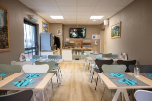 a classroom with tables and chairs and a kitchen at Comfort Aparthotel Besancon Hauts du Chazal in Besançon