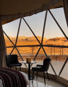 a room with a large window with two chairs and a table at WADI RUM REGENCY BUBBLE lUXURY in Wadi Rum