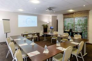 a conference room with tables and chairs and a screen at Comfort Aparthotel Bordeaux Begles Arena in Bègles