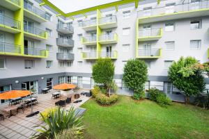 an apartment building with a courtyard with tables and umbrellas at Comfort Aparthotel Saint-Nazaire Les Portes de l Ocean in Saint-Nazaire